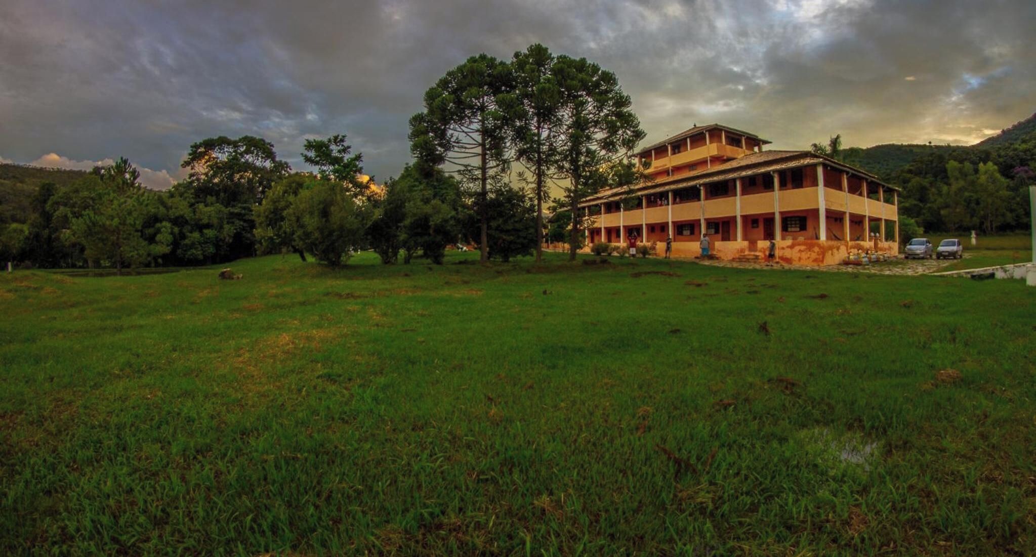 A large building with multiple floors, surrounded by a grassy field and trees.