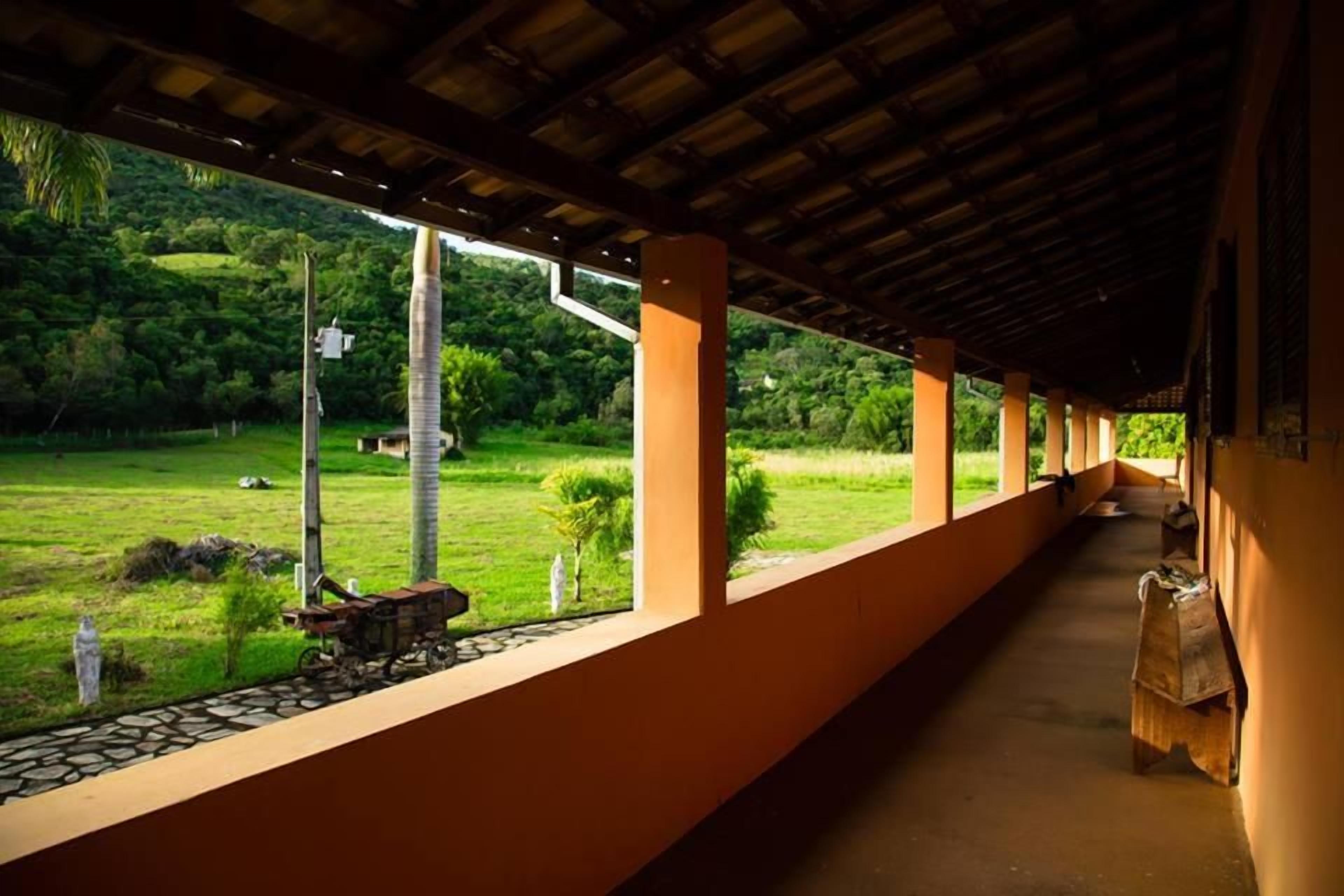 A covered corridor with a view of a green landscape.