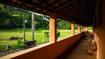 A covered corridor with a view of a green landscape.