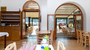 Un restaurant doté de mobilier en bois, d’un bar avec une sélection de verres, et offrant une vue sur le port.