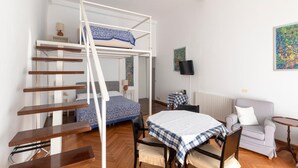 Una habitación pequeña con una cama litera, un escritorio, una silla y una mesita.