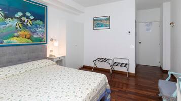 Une chambre à coucher avec un lit, une table de chevet, un tableau accroché au mur, une porte et une chaise.