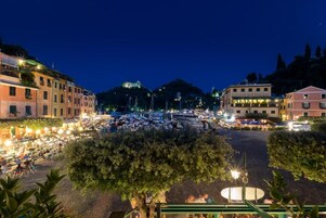 A marina with boats docked, surrounded by buildings with outdoor seating areas.