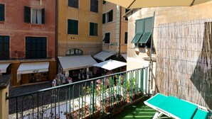 Un balcon donnant sur une rue, une chaise verte et une clôture en bambou.