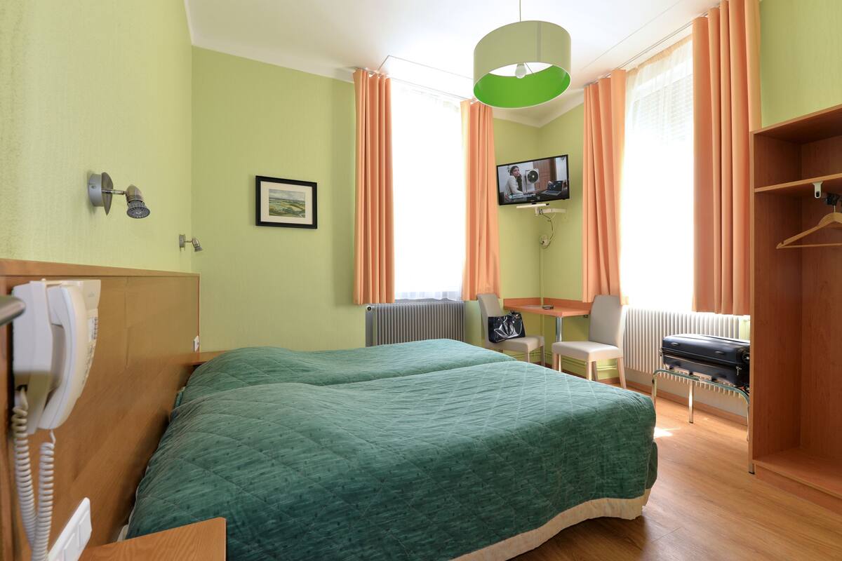 Una habitación de hotel con una cama grande, un escritorio, una silla, un televisor y un armario.