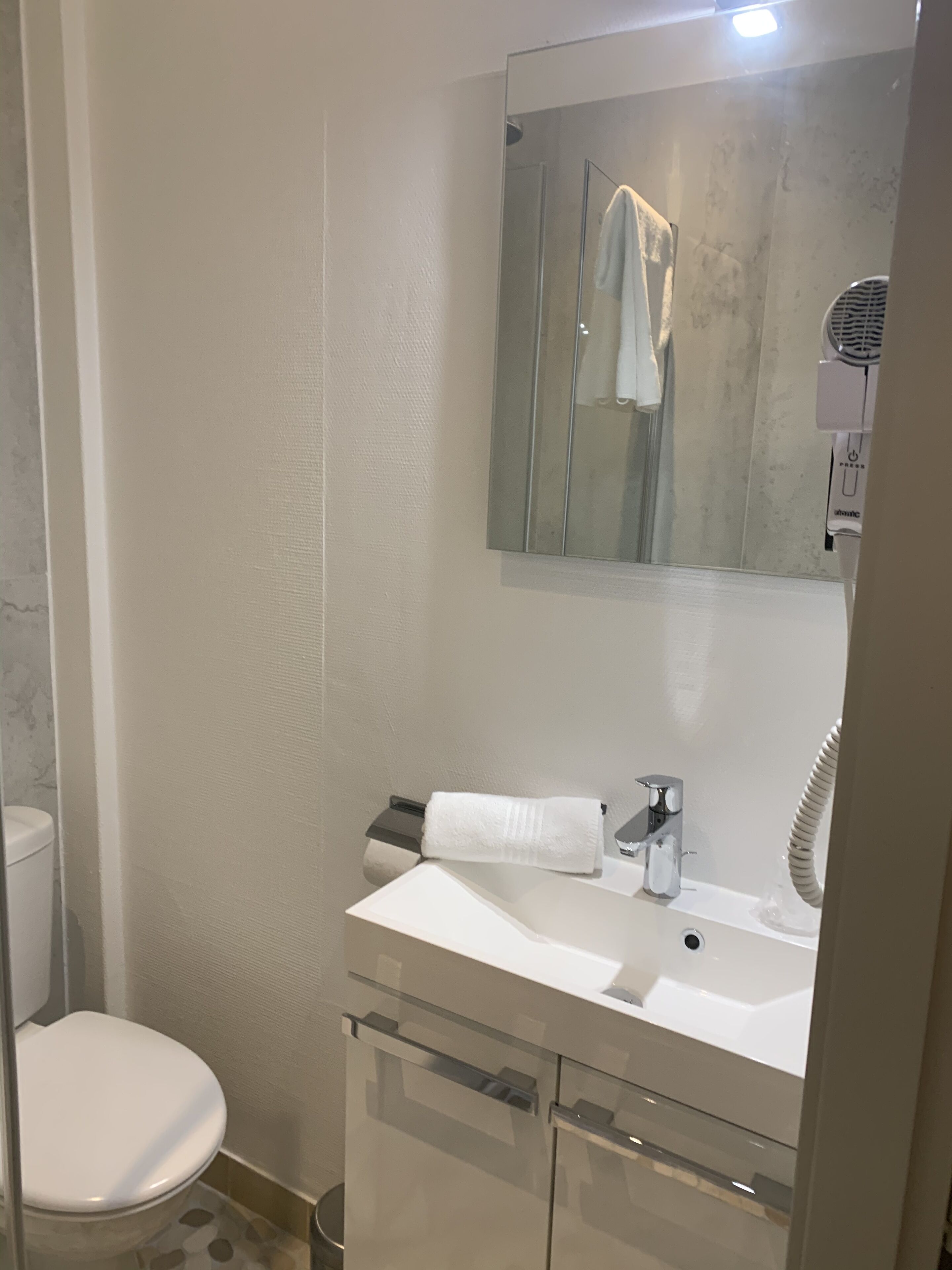 A modern bathroom with a white sink, a mirror, and a towel rack.