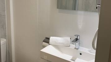 A modern bathroom with a white sink, a mirror, and a towel rack.