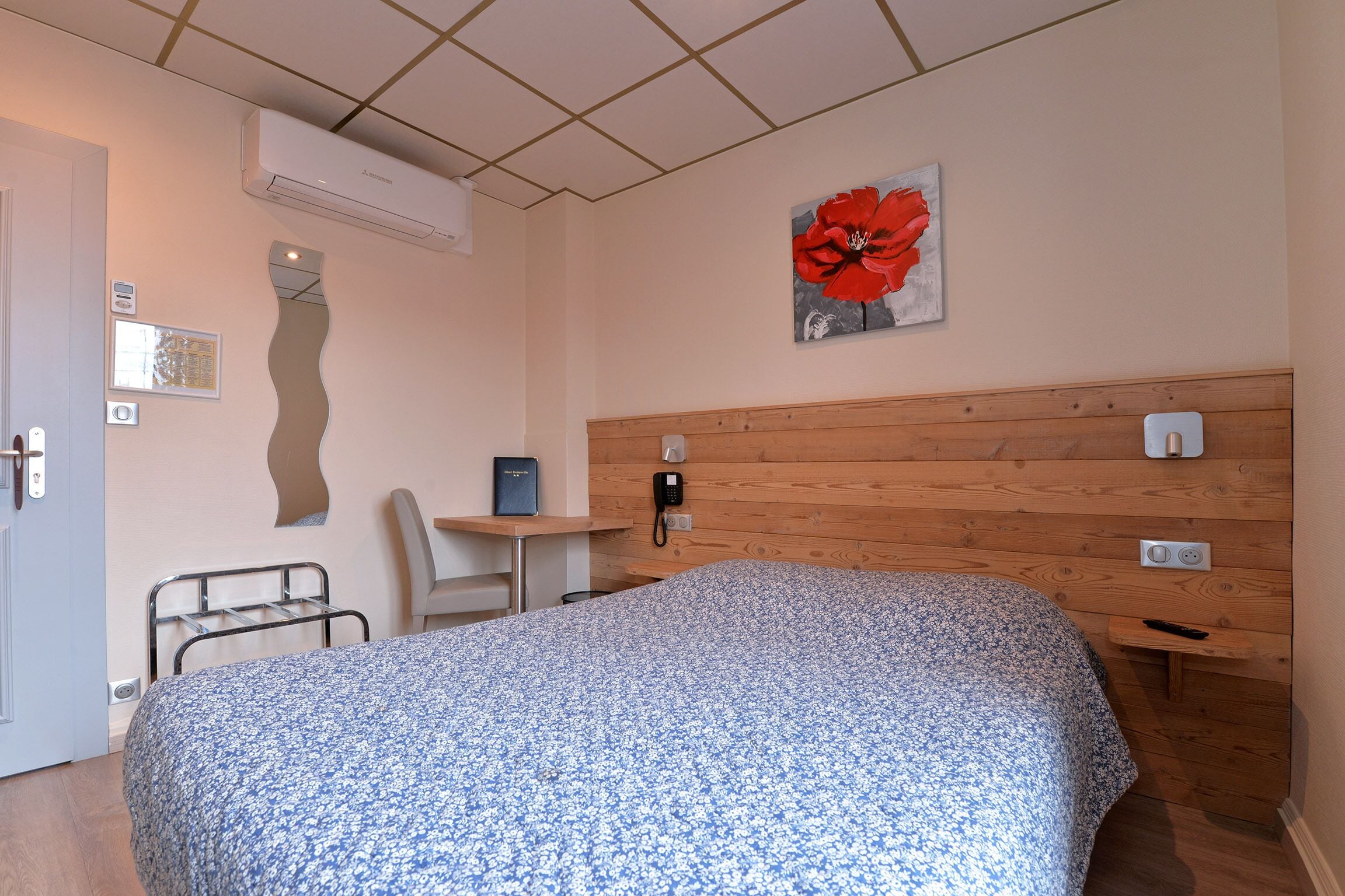 Un dormitorio con cama, escritorio, silla y teléfono.