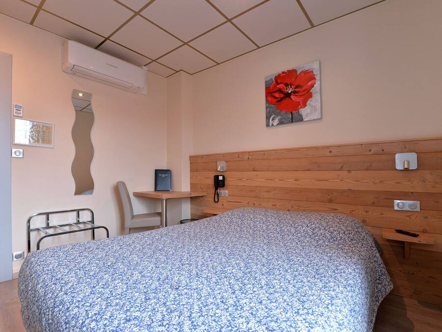 Une chambre à coucher avec un lit, un bureau, une chaise et un téléphone.