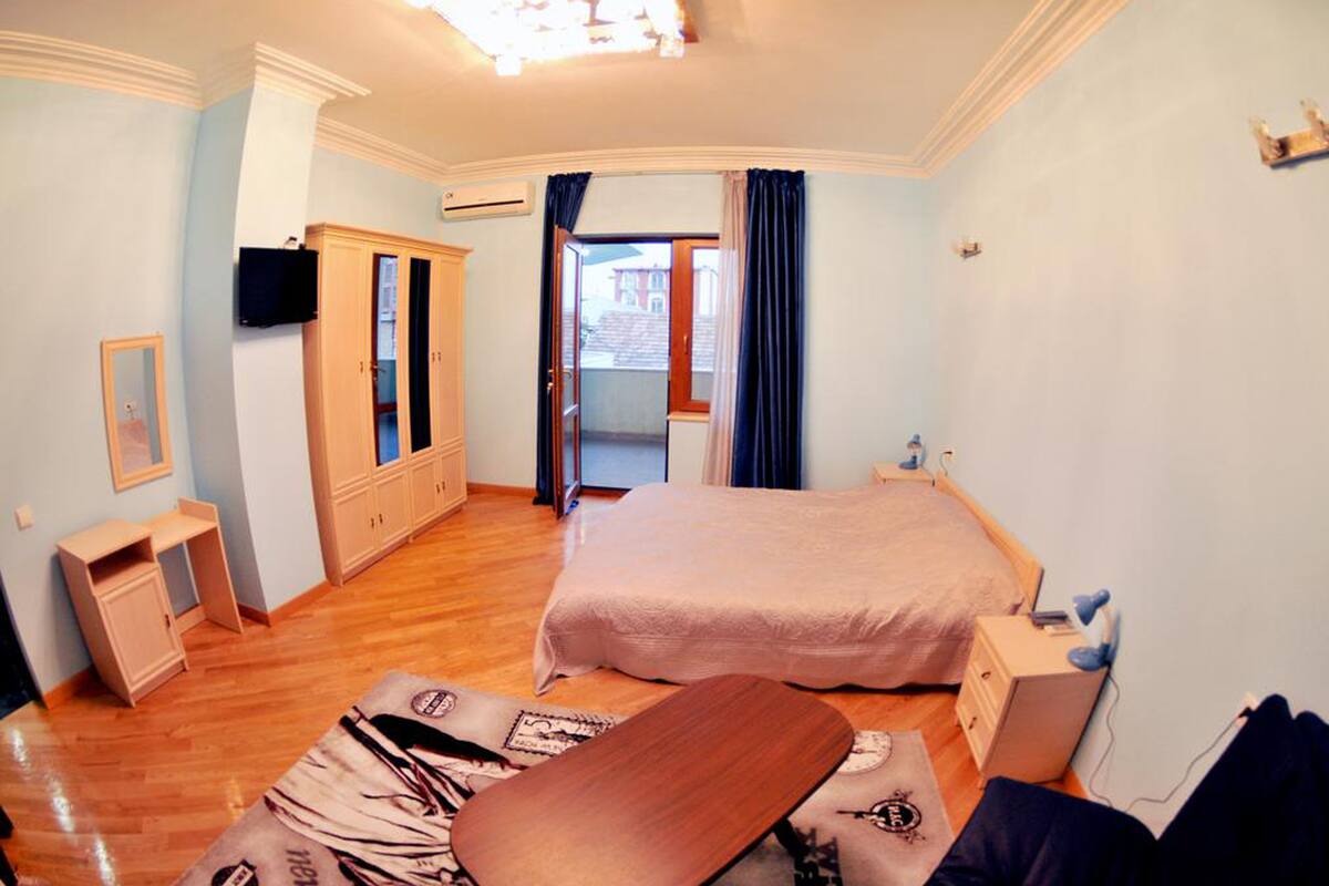 A bedroom with a bed, a desk, a wardrobe, and a television.