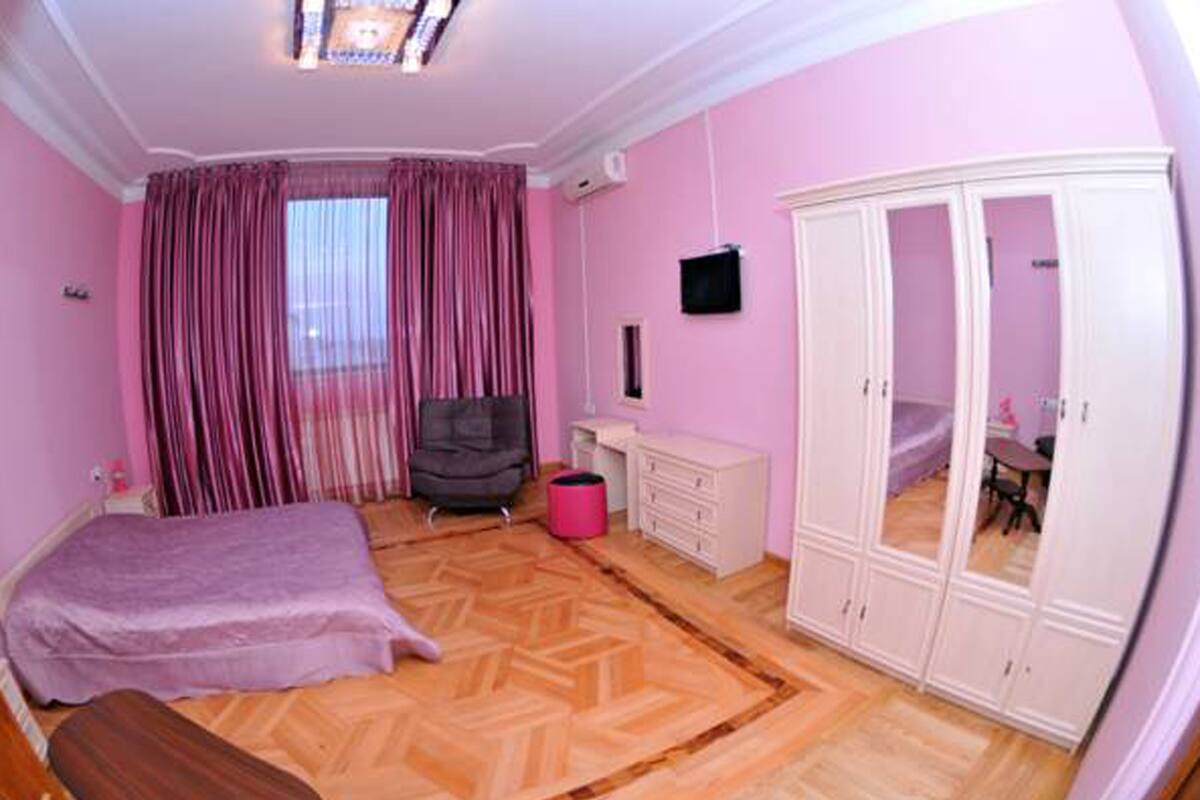 A bedroom with a bed, a desk, a chair, a wardrobe, and a window with curtains.