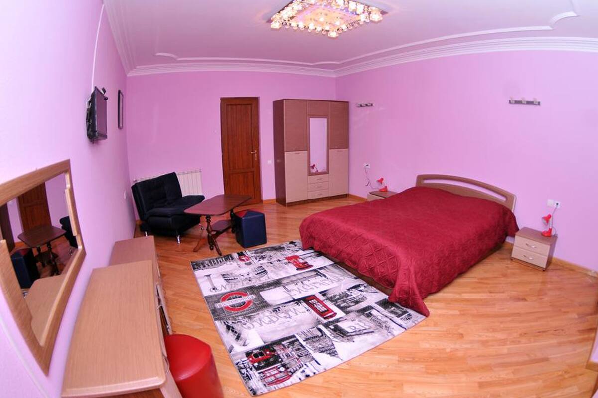 A bedroom with a bed, a desk, a chair, a dresser, and a mirror.