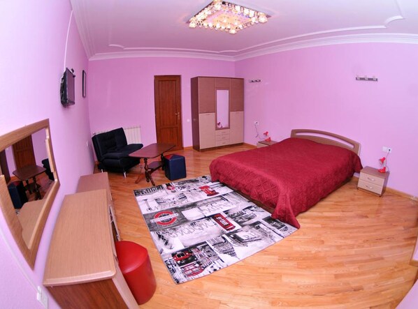 A bedroom with a bed, a desk, a chair, a dresser, and a mirror.