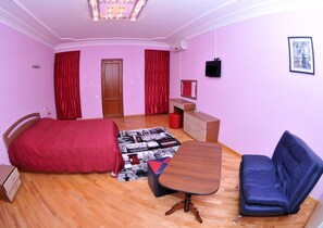 A bedroom with a bed, a desk, a chair, a dresser, and a red curtain.