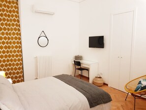 A bedroom with a bed, a desk, a chair, a TV, and a door. - BorgoAntico34 - Luxury Room (Molfetta)