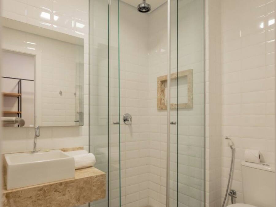 A modern bathroom with a glass-enclosed shower, a sink with a marble countertop, and a toilet.