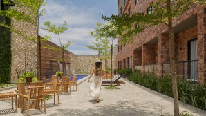A courtyard with outdoor seating, a swimming pool, and a brick building. - Pauli Boutique Hotel  (Fortaleza)