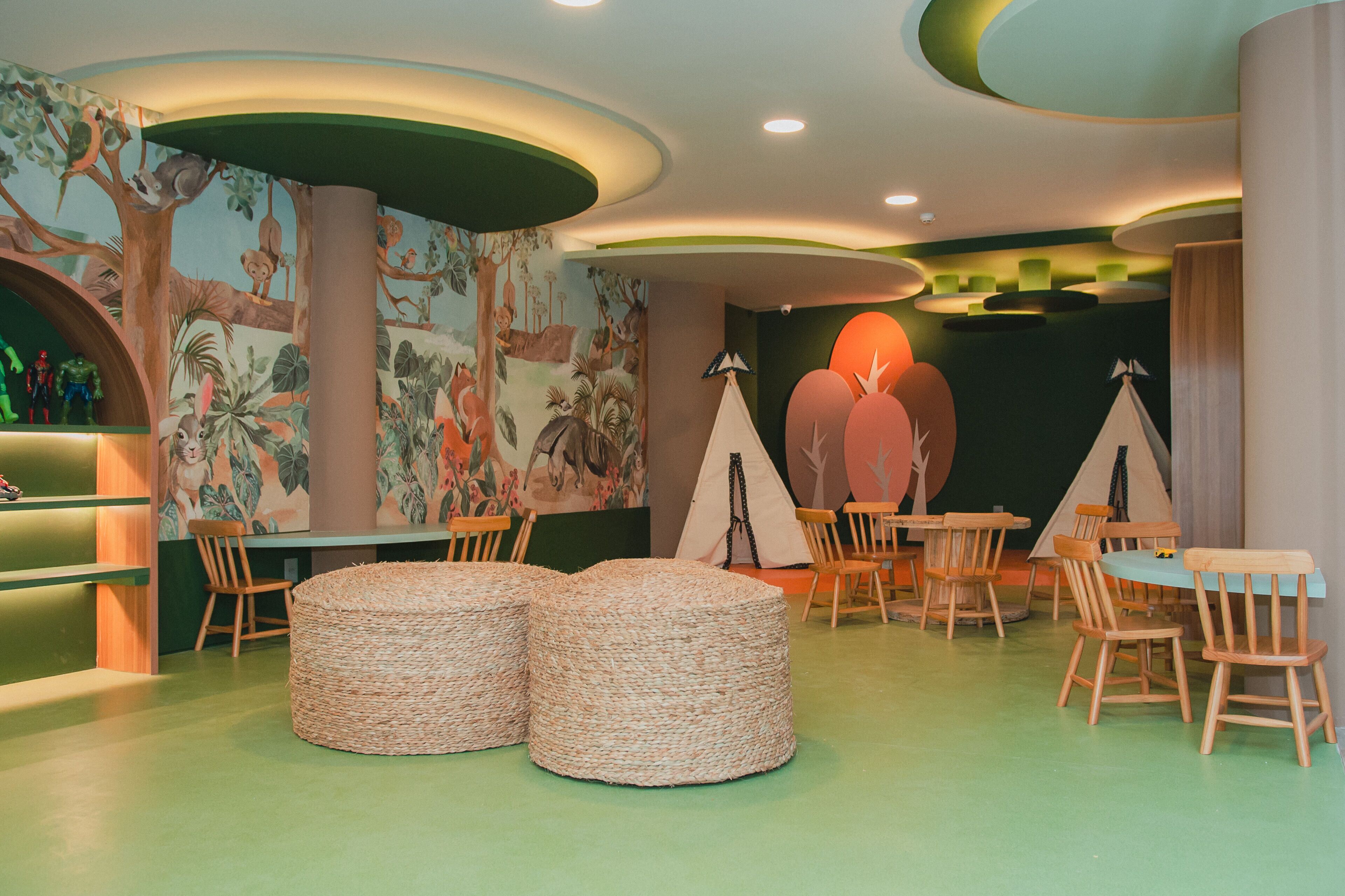 Ein Kinderspielbereich mit Tischen, Stühlen und einer Tier-Mural.