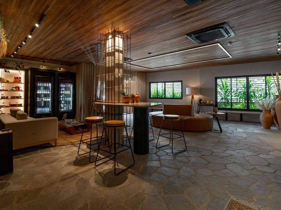 Un interior moderno con una zona de bar, asientos y un amplio ventanal con follaje exterior.