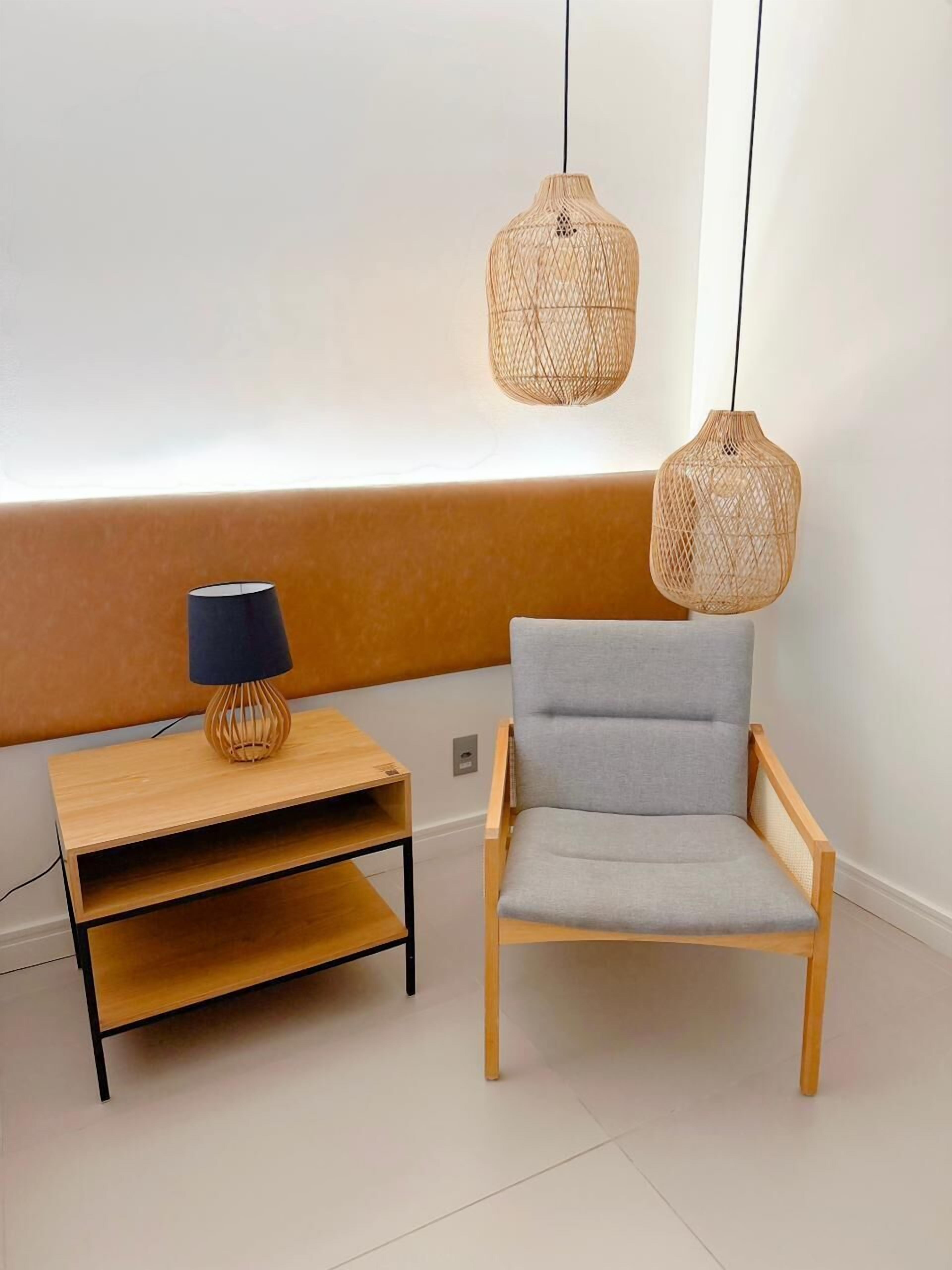 A modern room with a wooden bench, a grey chair, and two woven pendant lights.