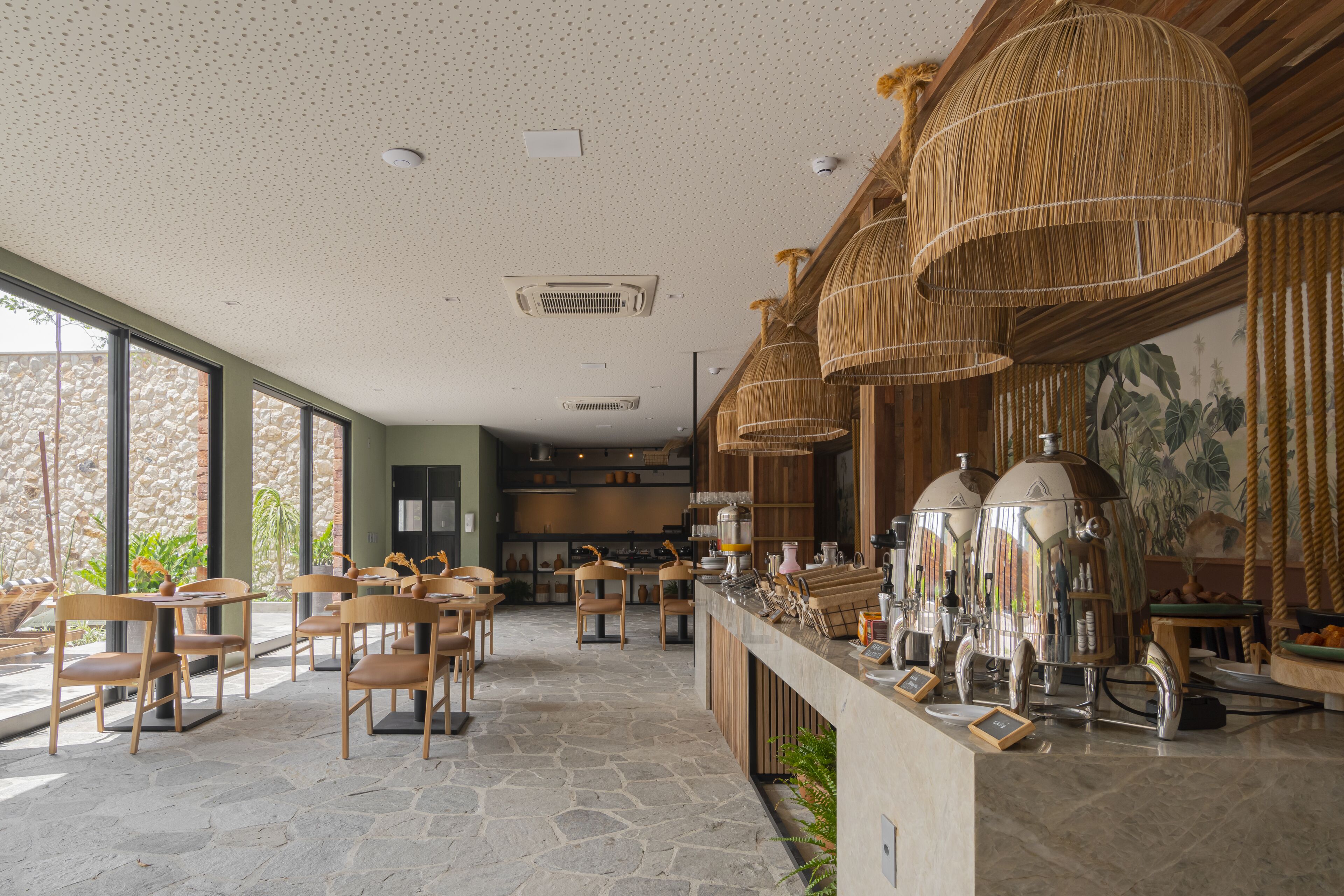 Ein geräumiges Café mit Steinböden, Holzstühlen und einer Theke mit Espressomaschinen.