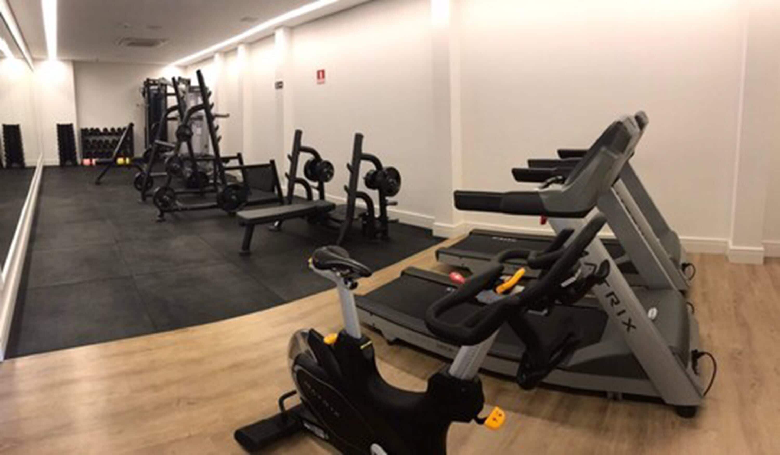 A gym with treadmills, weight machines, and a bench.