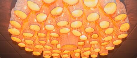 A large, circular chandelier with multiple orange and white light fixtures.