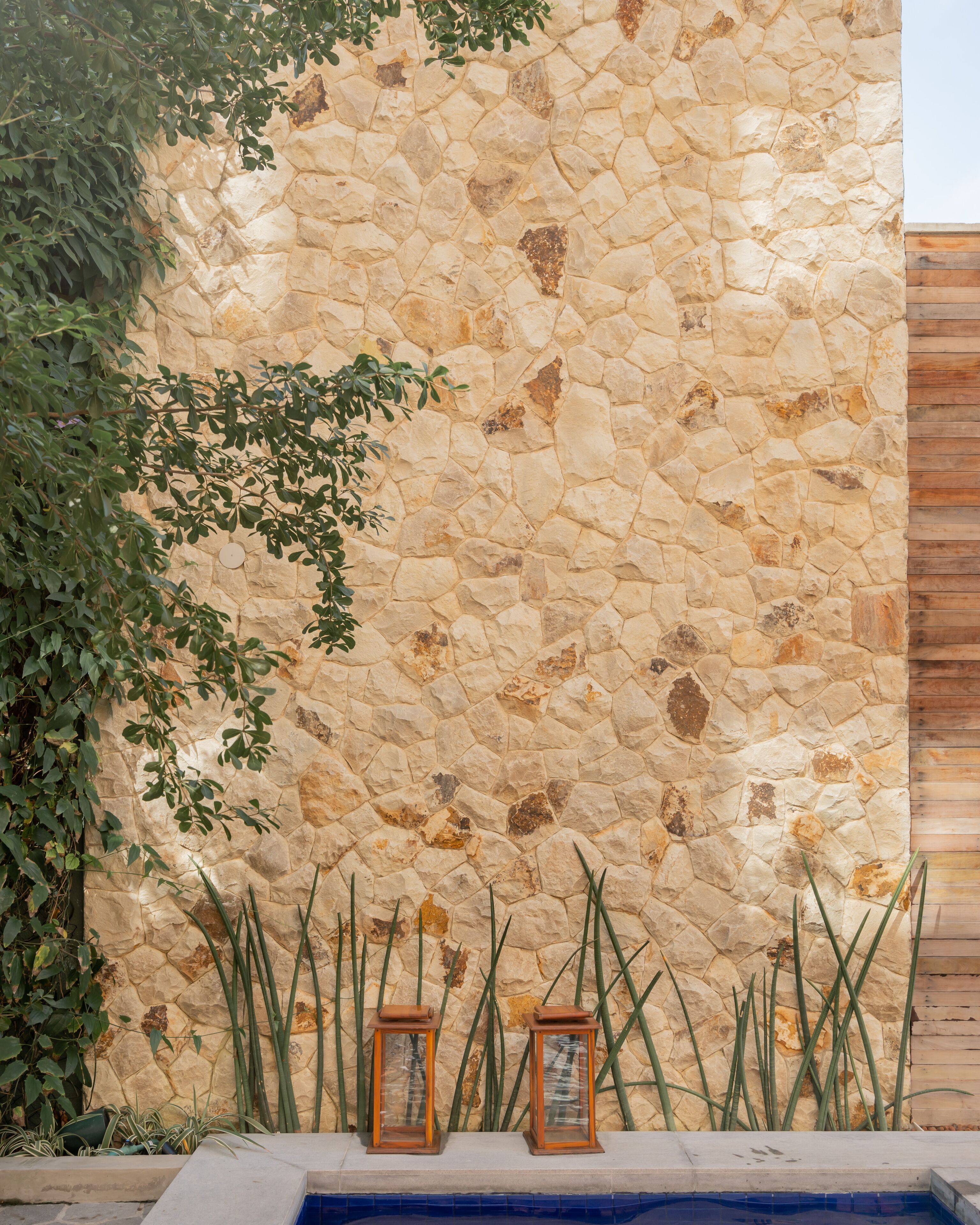 A stone wall with a pool and two lanterns.