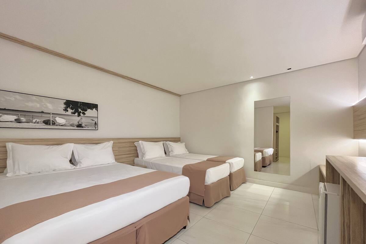 A hotel room with two beds, a large mirror, and a painting on the wall.