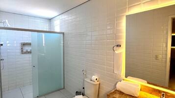 Un baño moderno con cabina de ducha de vidrio, inodoro y tocador con espejo.
