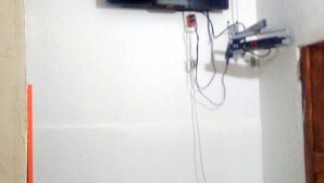 Une pièce équipée d’un téléviseur fixé au mur, d’une petite table et d’une prise électrique murale.