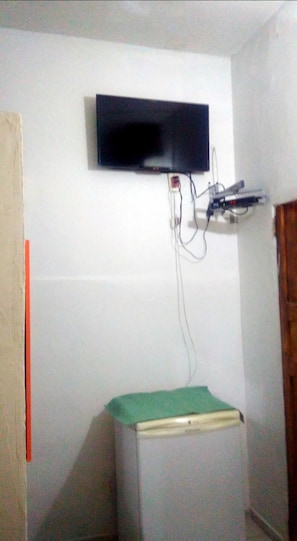 A room with a mounted television, a small table, and a wall-mounted electrical outlet. - Hospedaria Praia e Sol (Fortaleza)