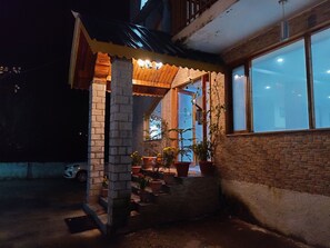 A covered outdoor area with a brick column, potted plants, and a car parked nearby. - Hotel Mountain Face by Snow City Hotels (Manali)