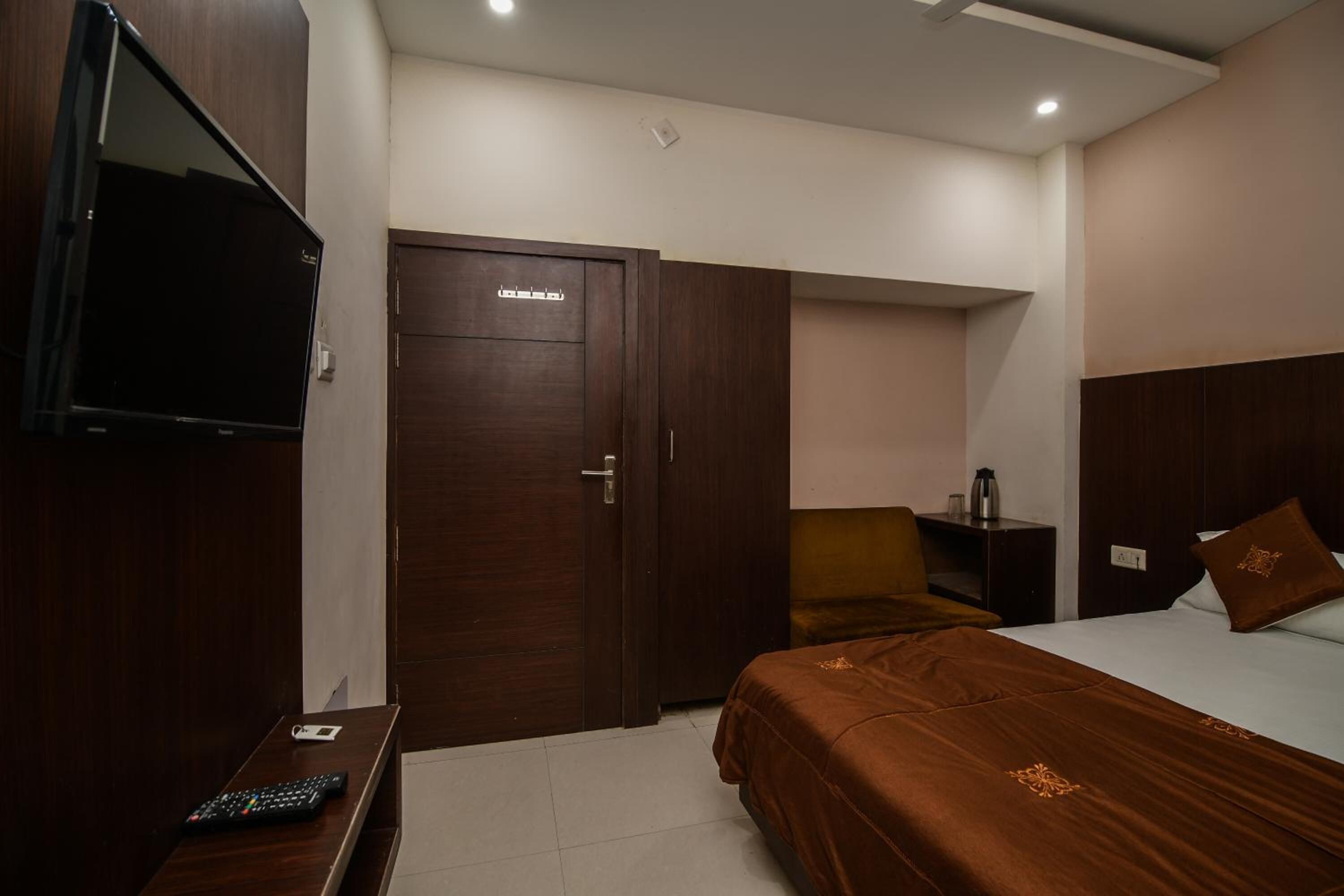 A hotel room with a bed, a TV, a desk, and a wardrobe.
