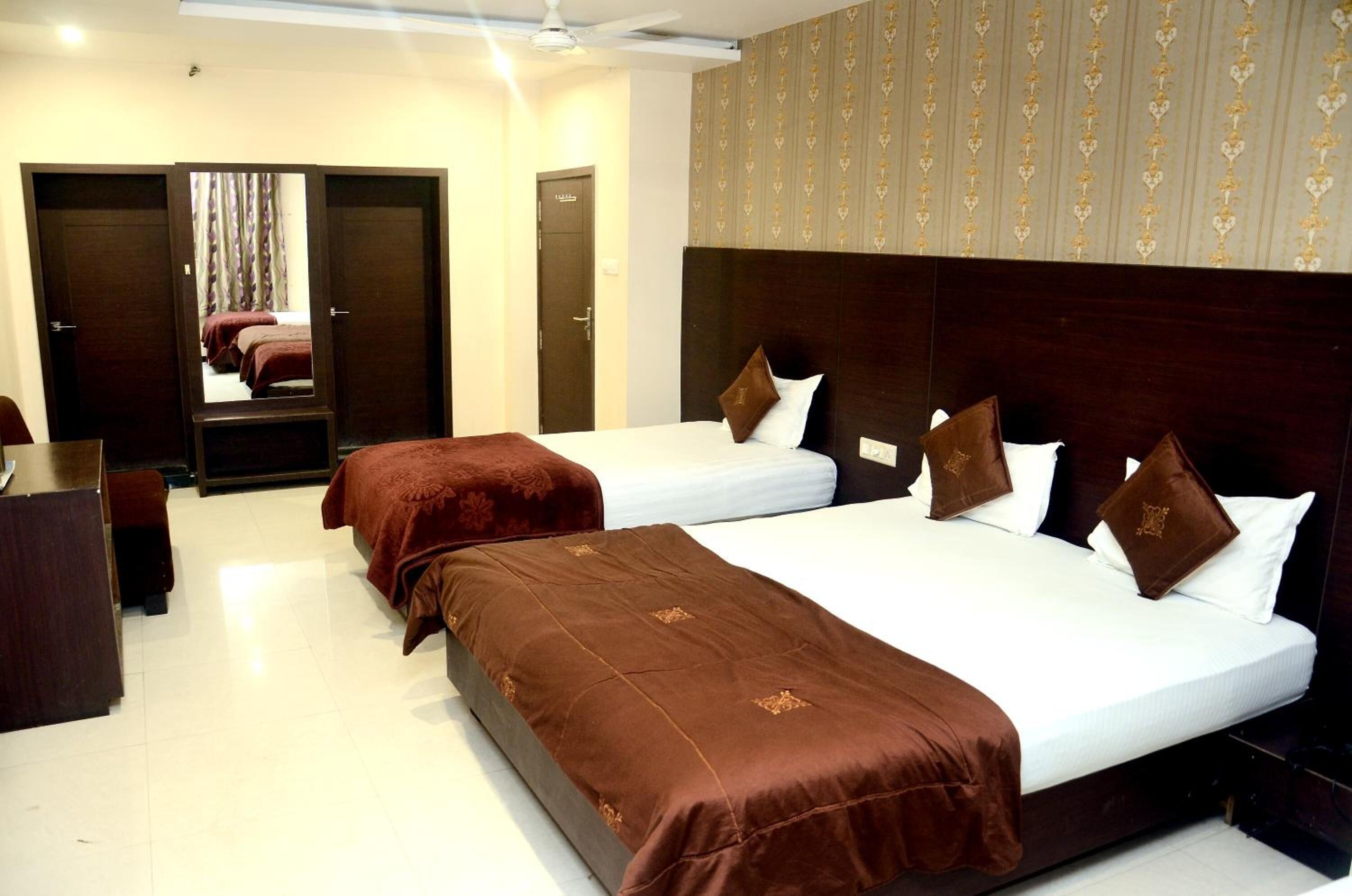 A hotel room with two beds, a wardrobe, and a mirror.