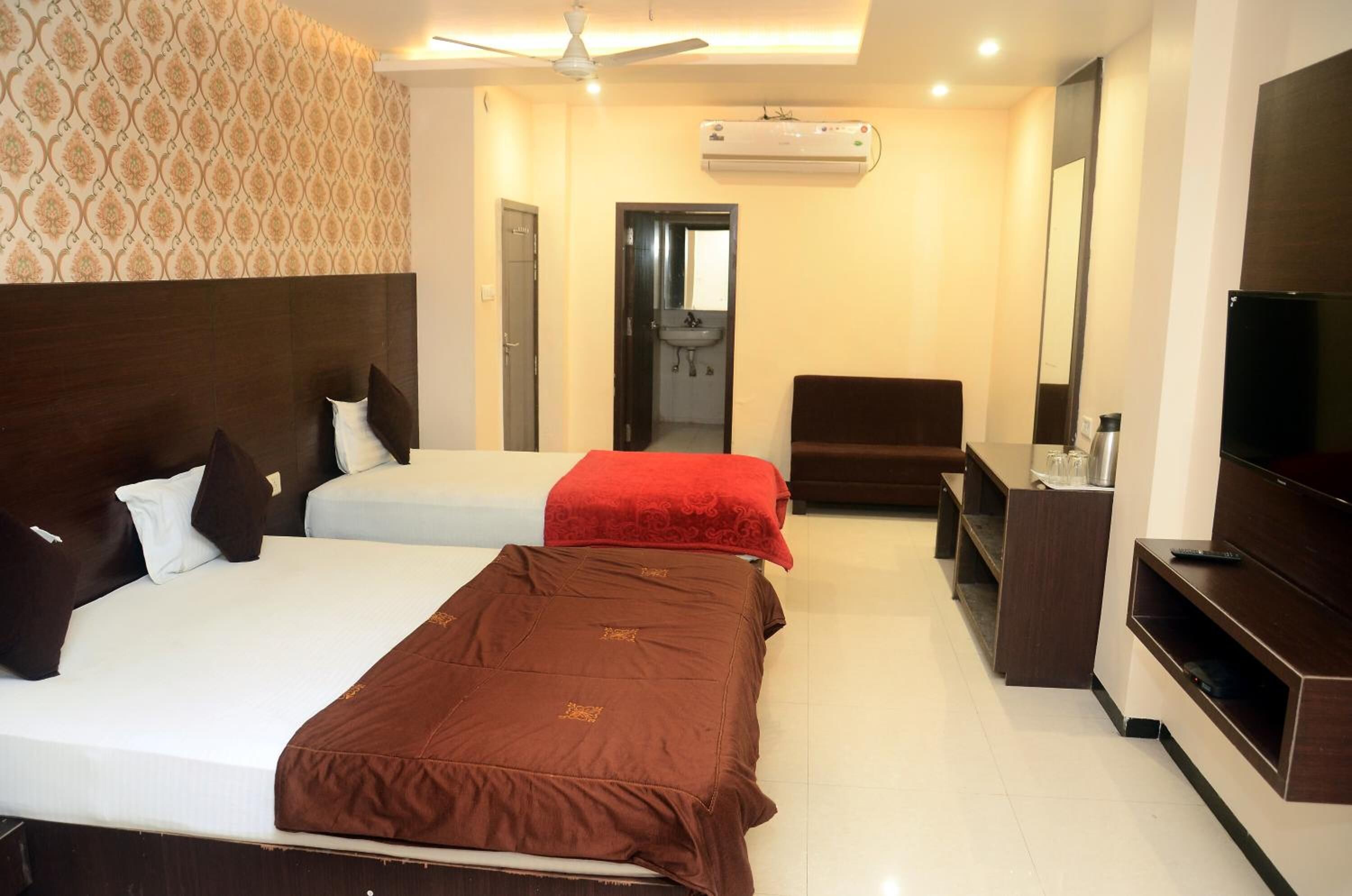 A hotel room with two beds, a TV, a desk, and a wardrobe.