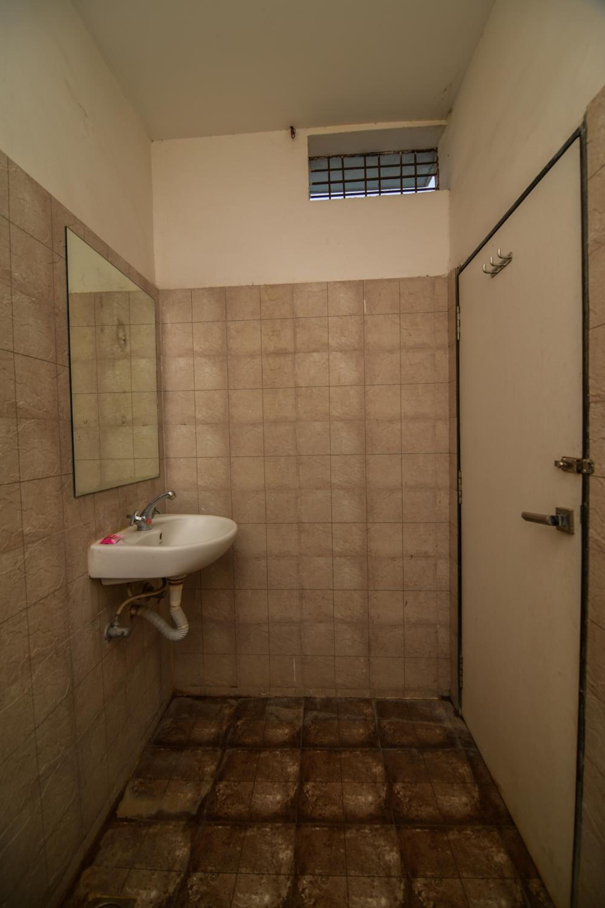 Une petite salle de bain avec un lavabo, un miroir et une porte.