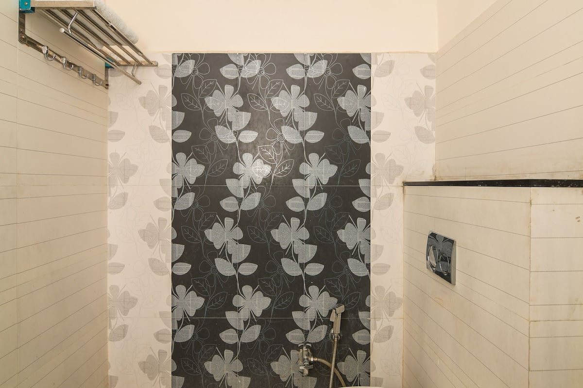 A small bathroom with a toilet, a shower, and a towel rack.