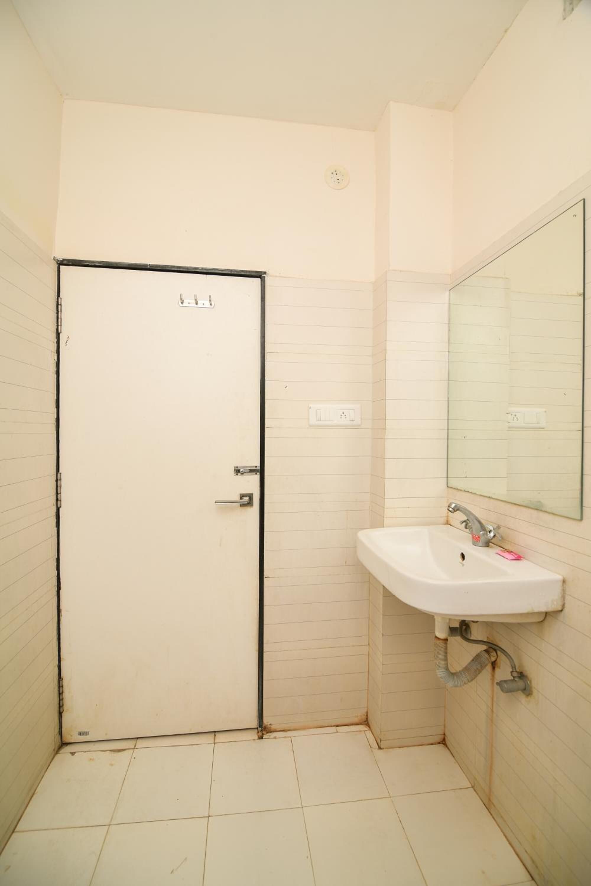 Une petite salle de bain propre, avec un lavabo blanc, un miroir et une porte.