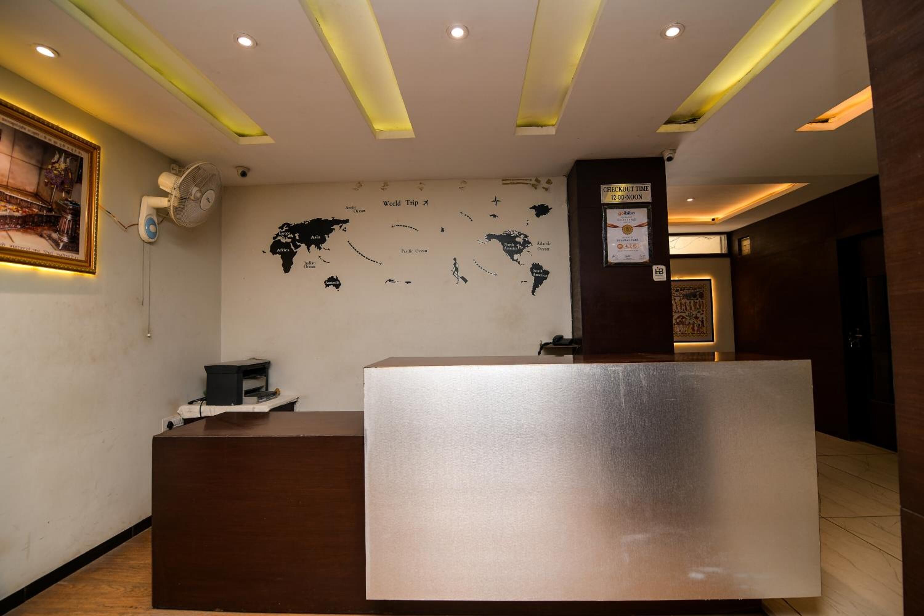 Un área de recepción con un mostrador de madera, un mapa mundial en la pared y un cartel que indica la hora de salida.