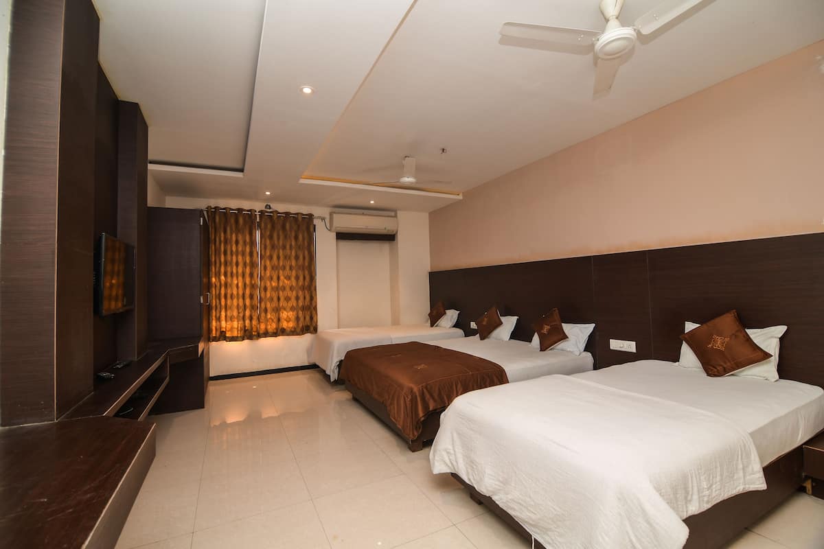 A hotel room with two beds, a flat-screen TV, a ceiling fan, and a window with curtains.