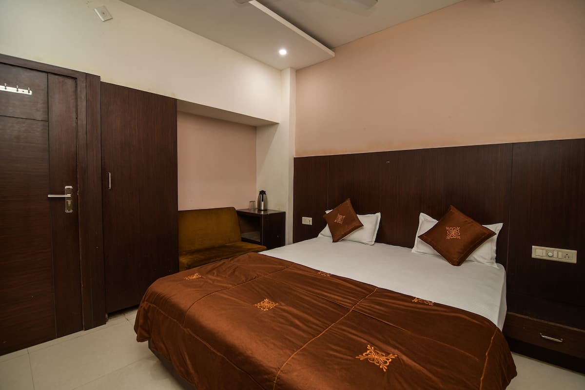 A hotel room with a large bed, a wardrobe, a nightstand, and a desk.