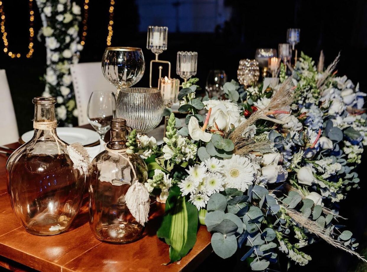 A table set with glassware, flowers, and candles.