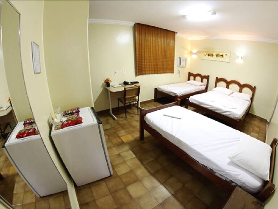 Una habitación de hotel con dos camas individuales, un escritorio con una silla y un refrigerador.
