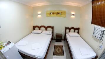 Habitación con dos camas individuales, una mesita, un calentador en la pared y una ventana con persianas.