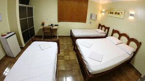 Habitación de hotel con dos camas individuales, un escritorio, una silla, un refrigerador pequeño y una ventana con persianas.