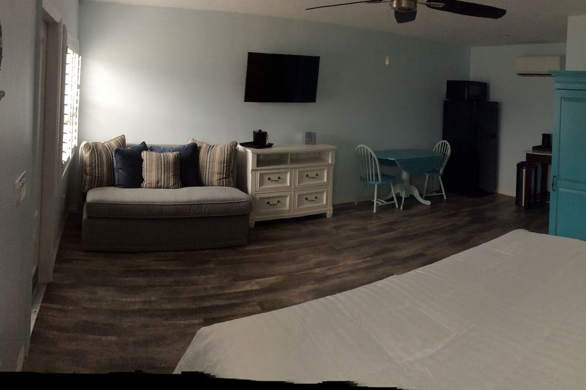 A bedroom with a bed, a dresser, a chair, a table, and a door.