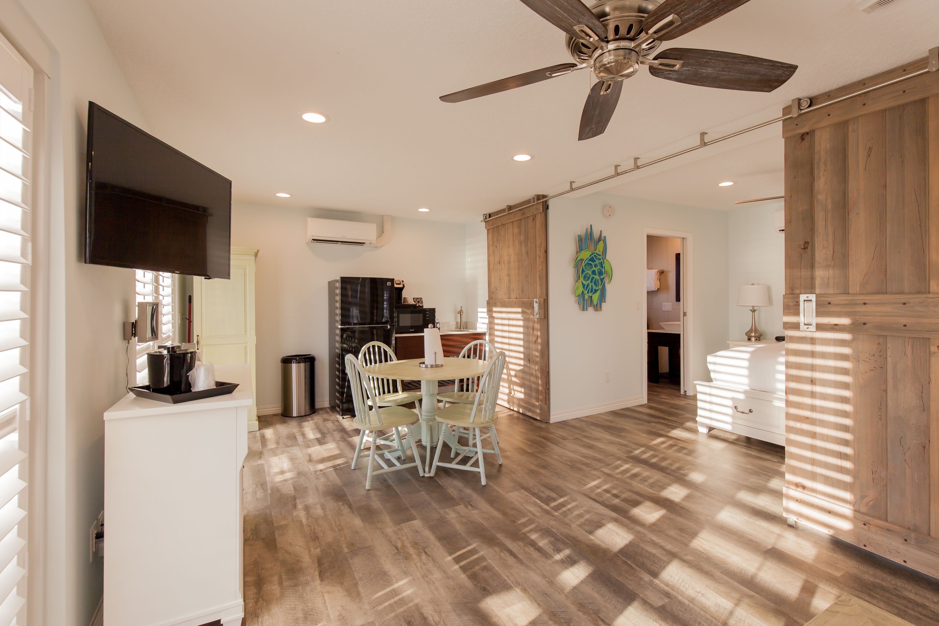 A spacious kitchen with a dining area, wooden flooring, and a ceiling fan.