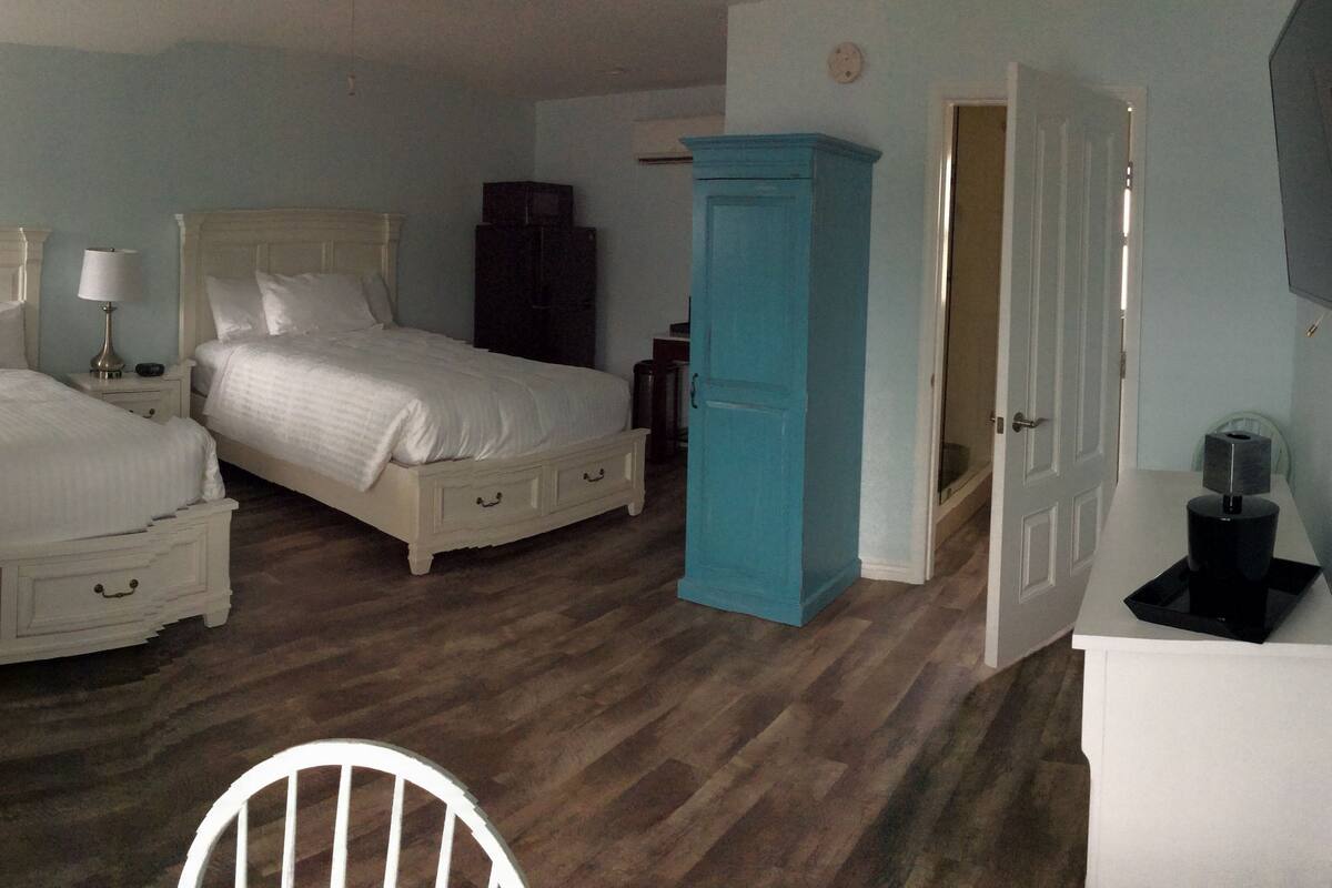 A bedroom with two beds, a wardrobe, a TV, and a desk.