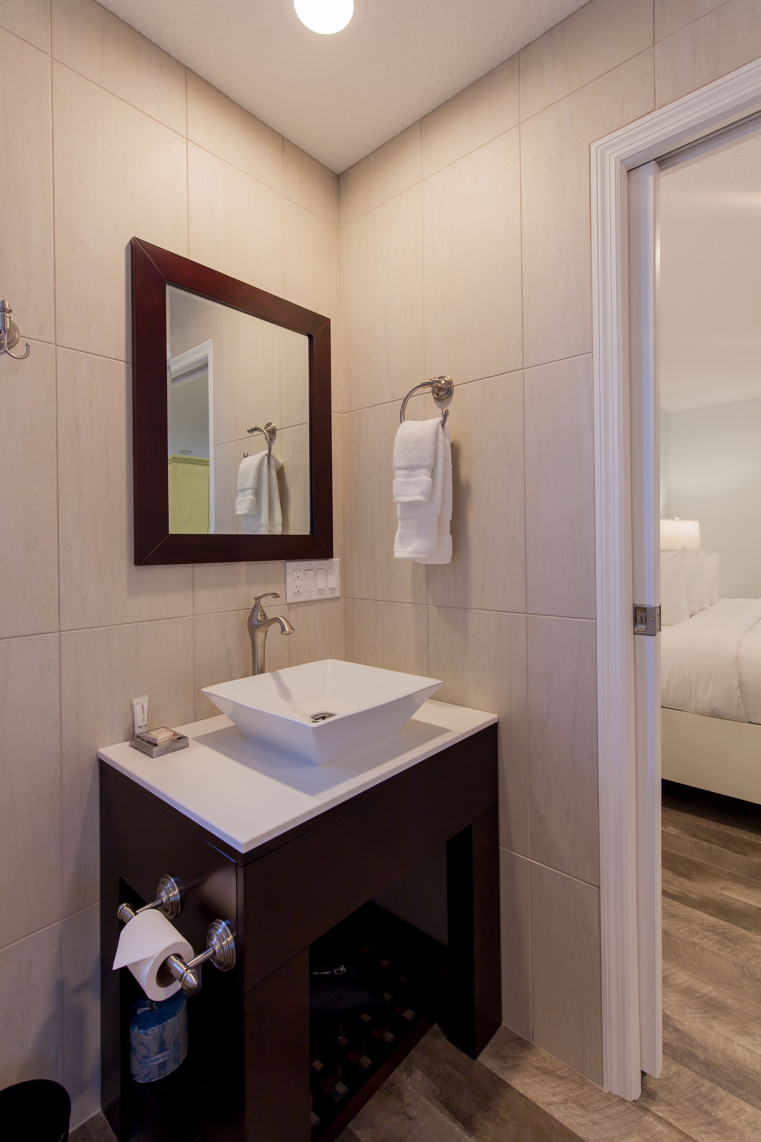 A modern bathroom with a white sink, a mirror, and a towel rack.
